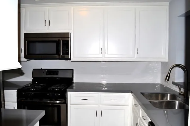 a kitchen with granite countertop white cabinets and black appliances
