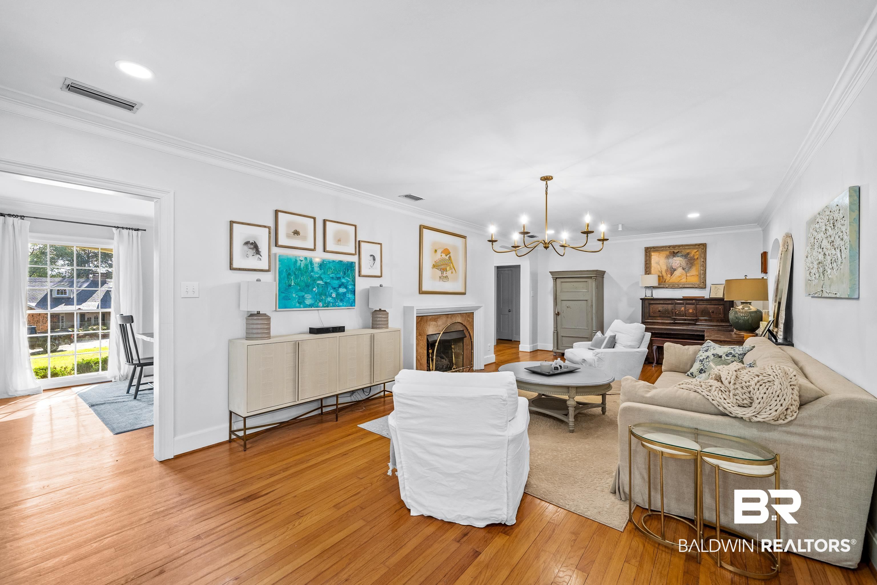141 Myrtlewood Lane Mobile, AL 36608 - Photo 15 of 44 Living room featuring crown molding, light wood finished floors, a fireplace, visible vents, and an inviting chandelier