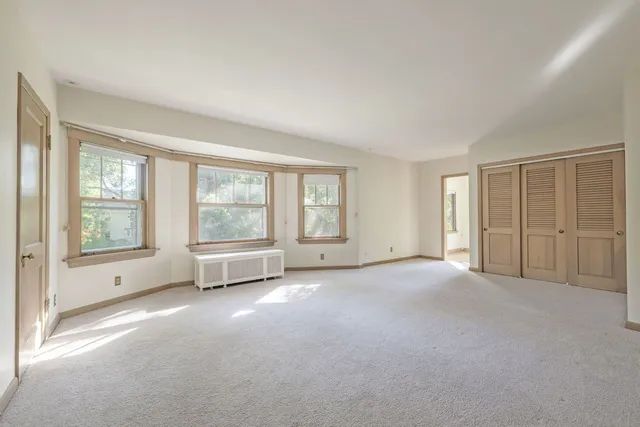 a view of a big room with windows and chandelier fan