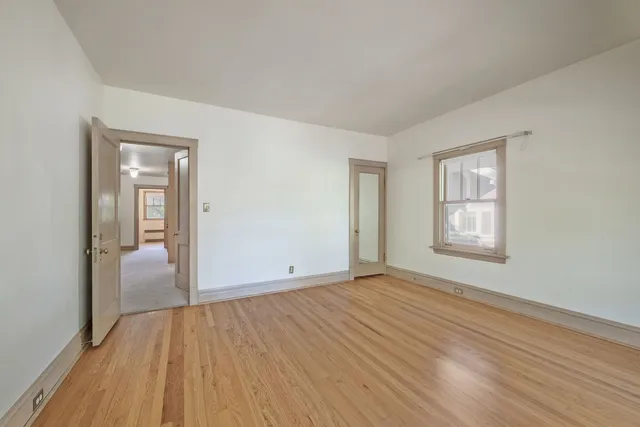 an empty room with wooden floor and windows