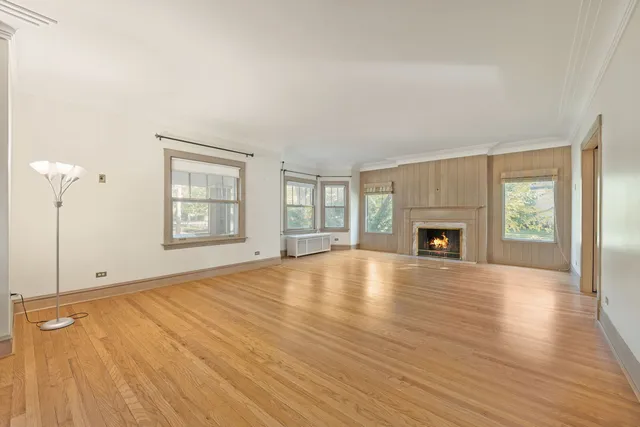 an empty room with wooden floor fireplace and windows