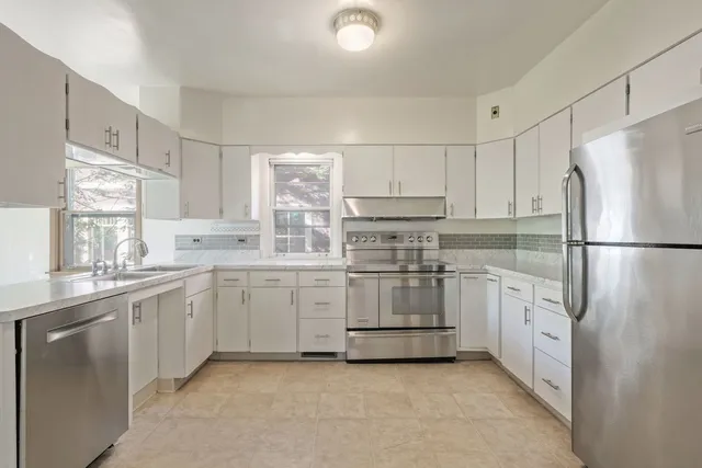 a kitchen with white cabinets and white stainless steel appliances