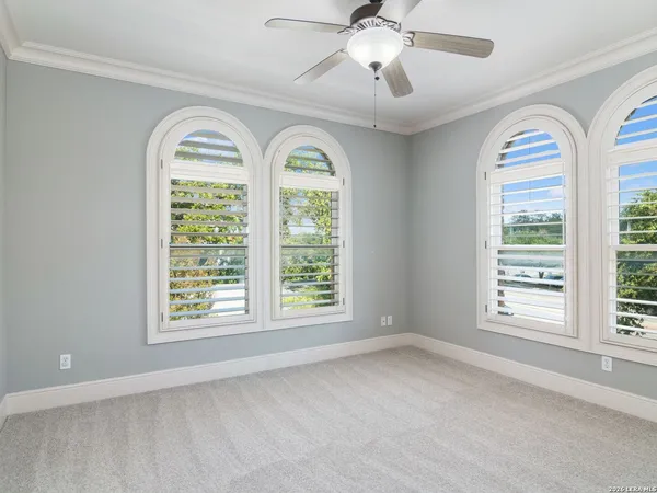 a view of empty room with windows and chandelier fan
