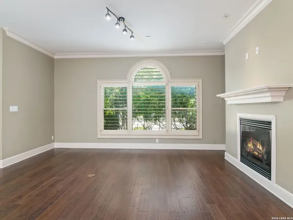 a view of an empty room with wooden floor fireplace and a window