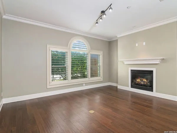 a view of an empty room with wooden floor fireplace and a window