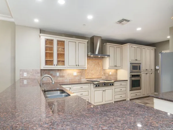 a kitchen with granite countertop a stove a sink and a refrigerator