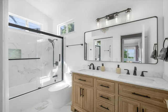 a bathroom with a granite countertop sink mirror toilet shower and bathtub