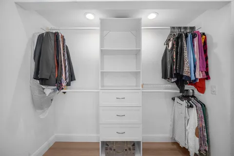 a view of walk in closet with clothes and shoes