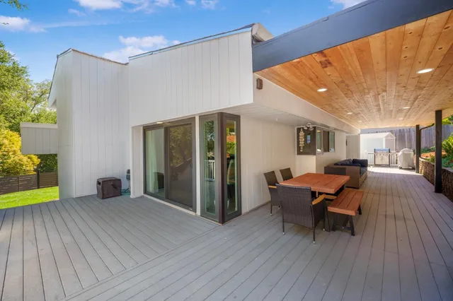 a view of a patio with table and chairs with wooden floor and fence
