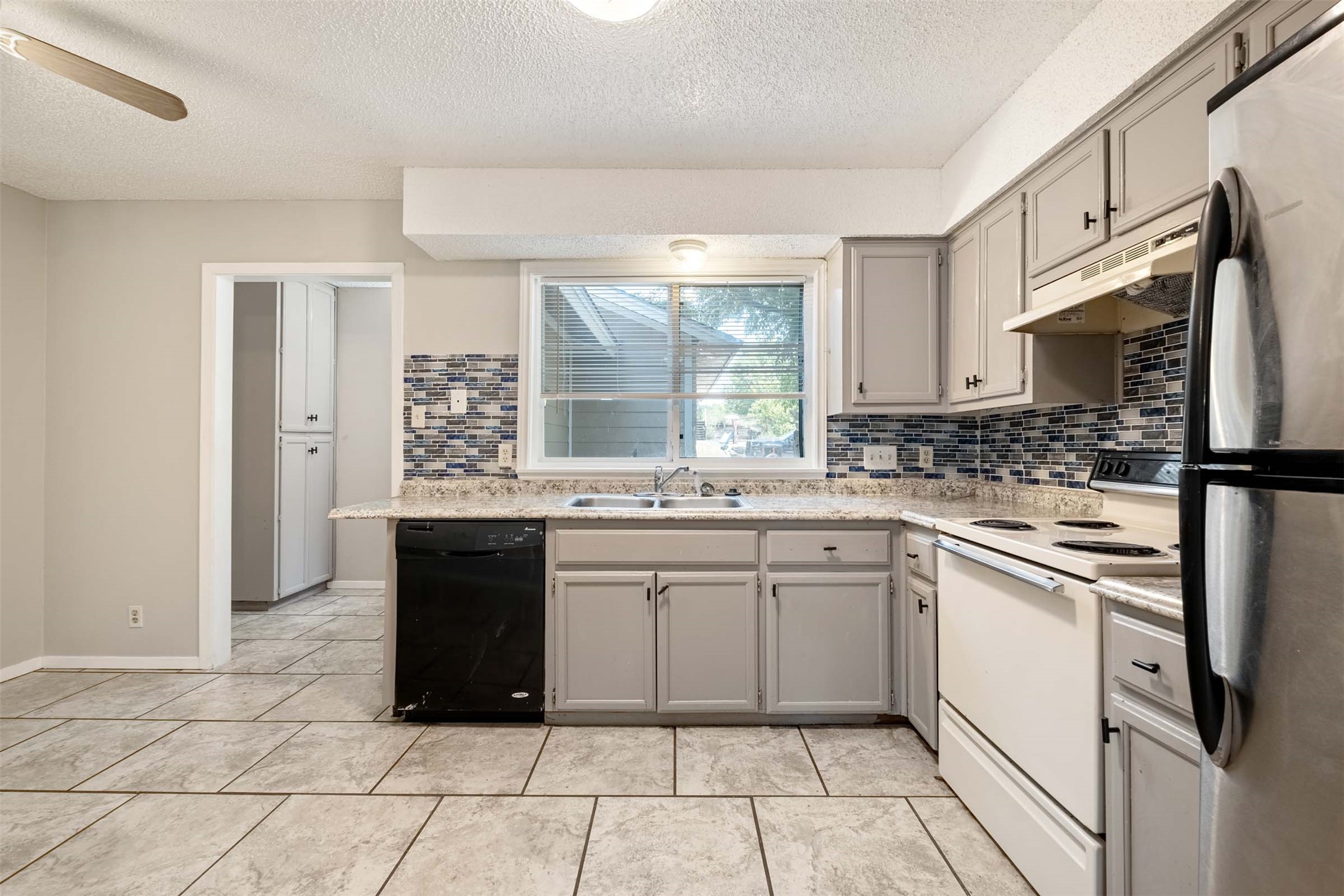 Kitchen featuring gray cabinets, white electric range oven, freestanding refrigerator, black dishwasher, and a textured ceiling