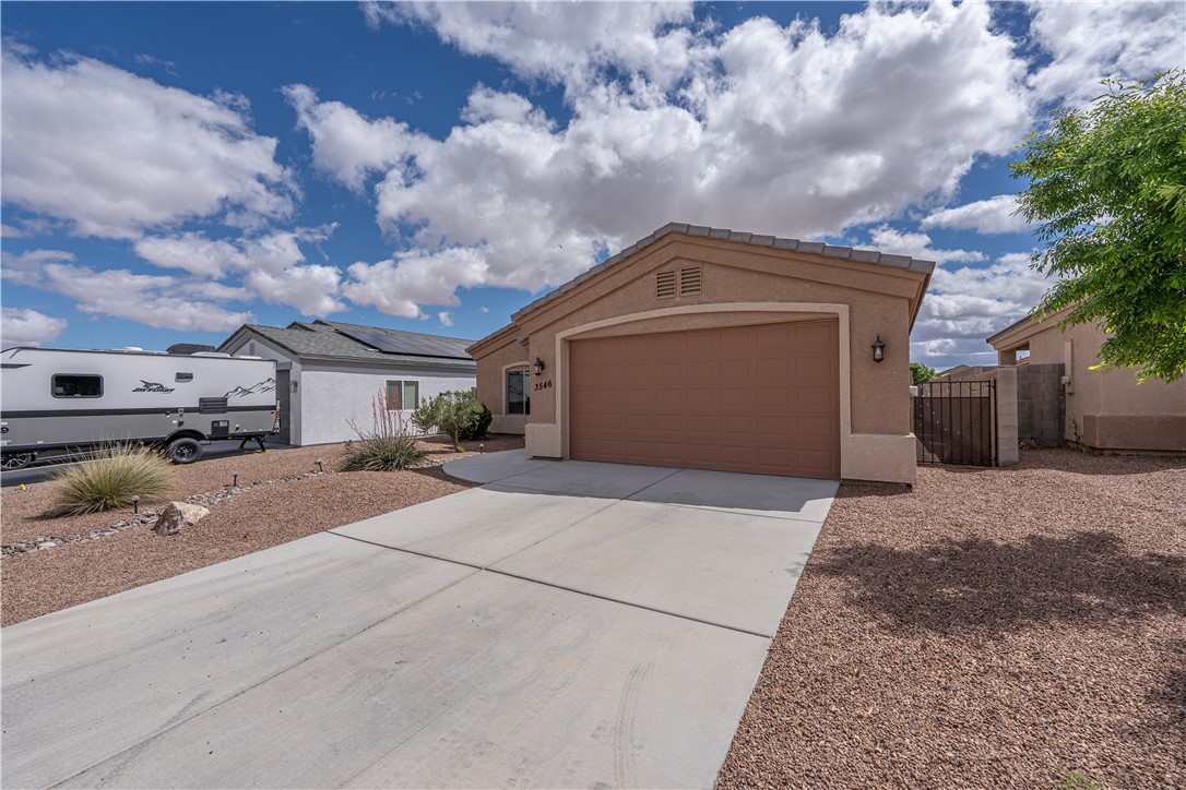3546 North Kenneth Road Kingman, AZ 86409 - Photo 28 of 35 The property features a concrete driveway leading to an attached garage with a brown door