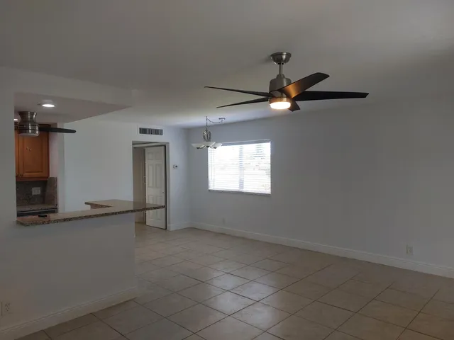 an empty room with ceiling fan and window