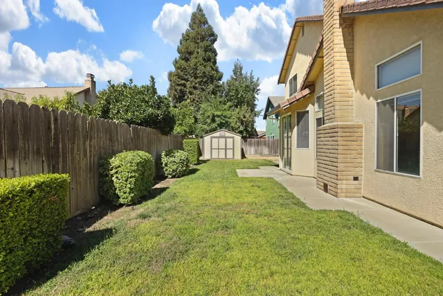 a view of a house with a yard and large tree
