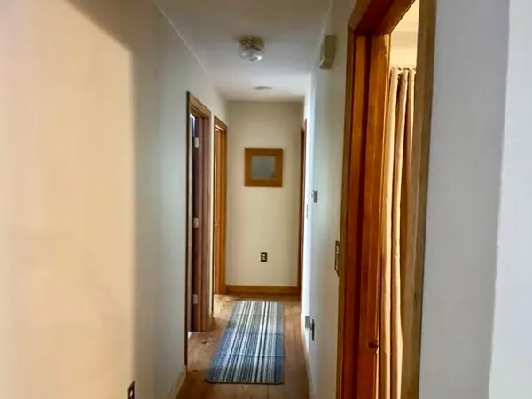 a view of a hallway with wooden floor and stairs