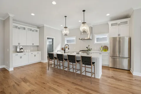 a kitchen with stainless steel appliances granite countertop a refrigerator a sink dishwasher a stove and white cabinets with wooden floor