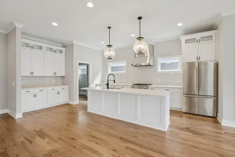 a kitchen with stainless steel appliances granite countertop a refrigerator a sink dishwasher a oven and white cabinets with wooden floor