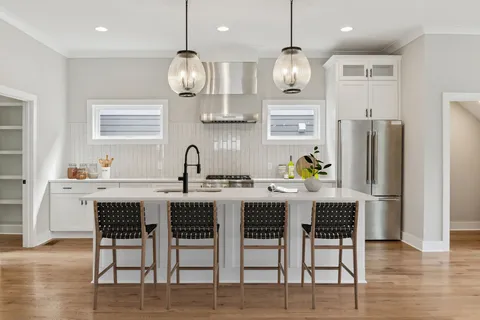 a kitchen with stainless steel appliances granite countertop a dining table chairs sink refrigerator and microwave