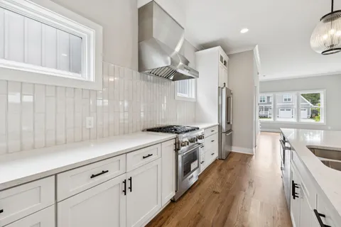 a kitchen with cabinets wooden floor and stainless steel appliances