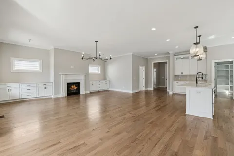 a view of a kitchen and an empty room with wooden floor