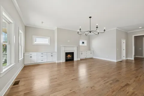 an empty room with wooden floor fireplace and windows