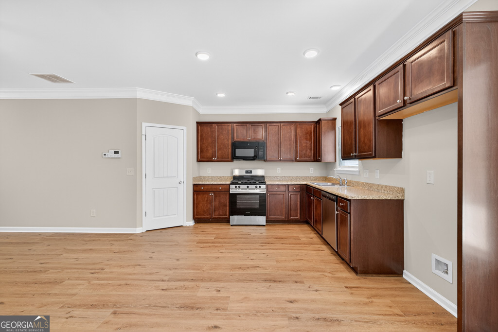 1734 Snapping Court Winder, GA 30680 - Photo 9 of 35 a large kitchen with stainless steel appliances granite countertop a stove a sink dishwasher and a refrigerator with wooden floor