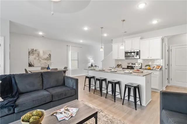 a living room with stainless steel appliances kitchen island granite countertop a couch and cabinets