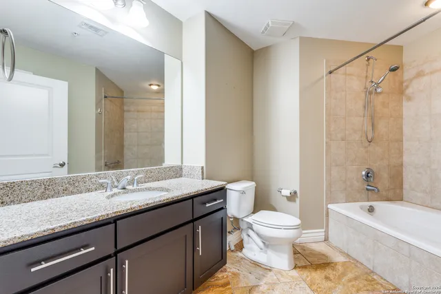 a bathroom with a granite countertop sink a toilet and a bathtub