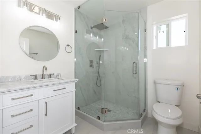 a bathroom with a granite countertop toilet sink shower and mirror