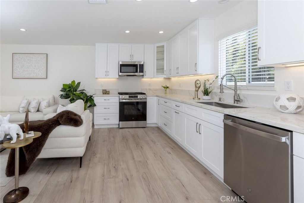 15254 Clymer Street Mission Hills, CA 91345 - Photo 6 of 26 a large white kitchen with stainless steel appliances granite countertop a stove a sink dishwasher and a refrigerator with wooden floor