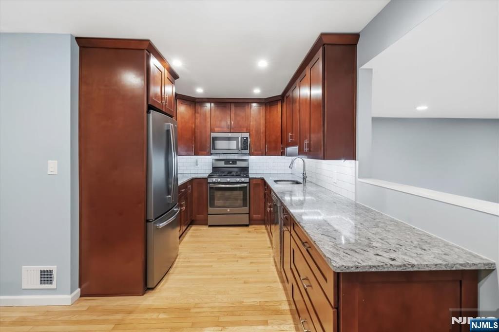 117 Sunset Key, Unit 117 Secaucus, NJ 07094 - Photo 6 of 22 a kitchen with stainless steel appliances granite countertop a refrigerator a stove and a sink with wooden floor