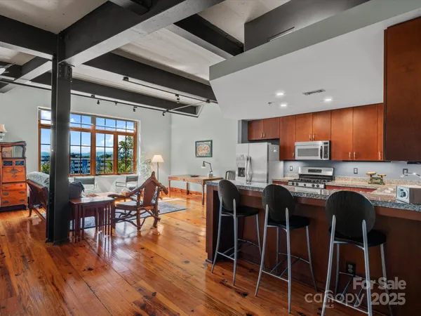 a kitchen with stainless steel appliances a dining table chairs stove and wooden floor