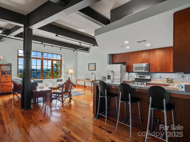 a kitchen with stainless steel appliances a dining table chairs stove and wooden floor