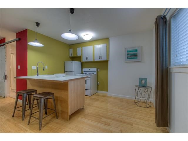 304 East 33rd Street, Unit 2 Austin, TX 78705 - Photo 9 of 12 a kitchen with kitchen island granite countertop a sink cabinets and wooden floor