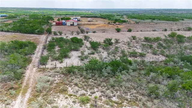 a view of a dry yard with trees and houses