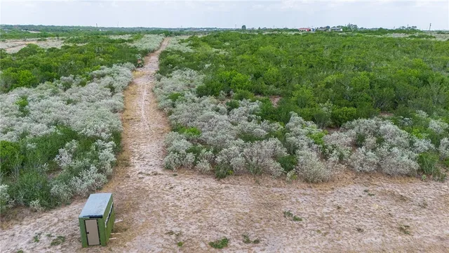 an aerial view of a houses with outdoor space and trees all around