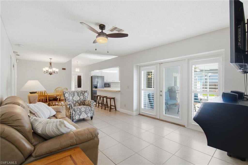 3022 47th Street Southwest Naples, FL 34116 - Photo 23 of 46 Open-concept living area featuring light tile flooring, a ceiling fan, and white French doors with louvered inserts providing access to the exterior