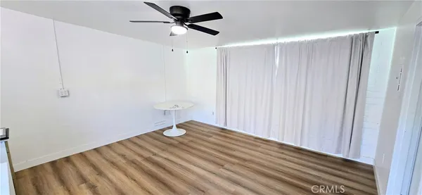 a view of a room with a wooden floor and a ceiling fan