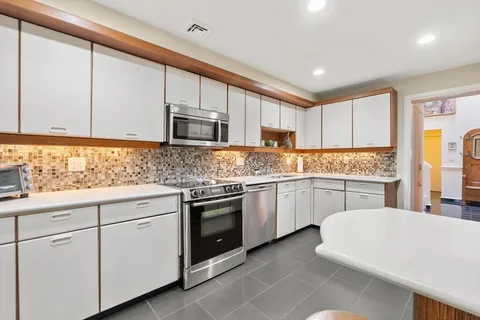 a kitchen with kitchen island granite countertop white cabinets white stainless steel appliances with a sink and dishwasher