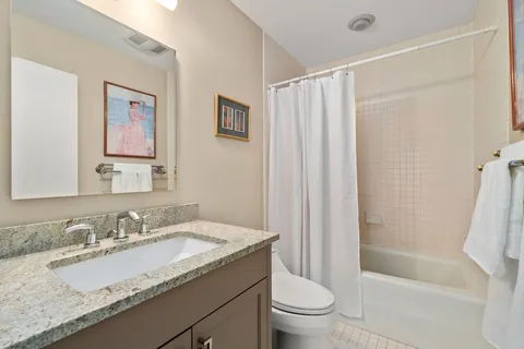 a bathroom with a granite countertop sink a toilet and shower