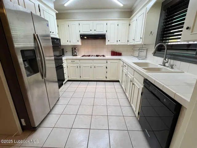 a kitchen with a sink a refrigerator a stove a washer dryer and white cabinets
