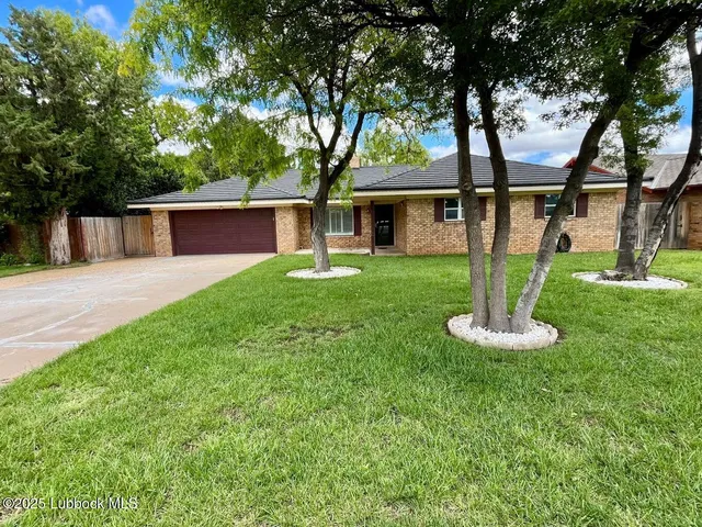 a front view of a house with a yard and trees