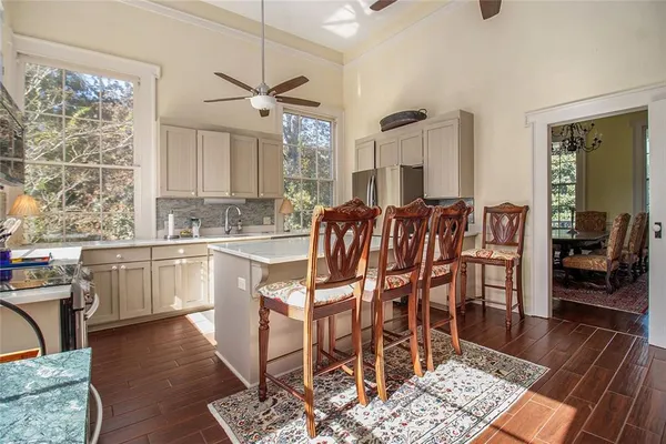 a kitchen with stainless steel appliances granite countertop a stove top oven a sink a dining table and chairs with wooden floor