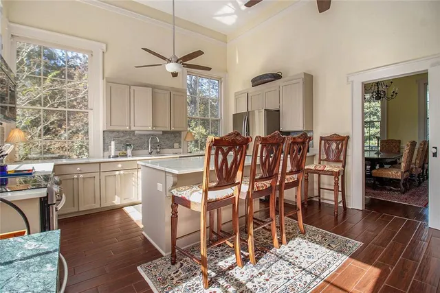 a kitchen with stainless steel appliances granite countertop a stove top oven a sink a dining table and chairs with wooden floor