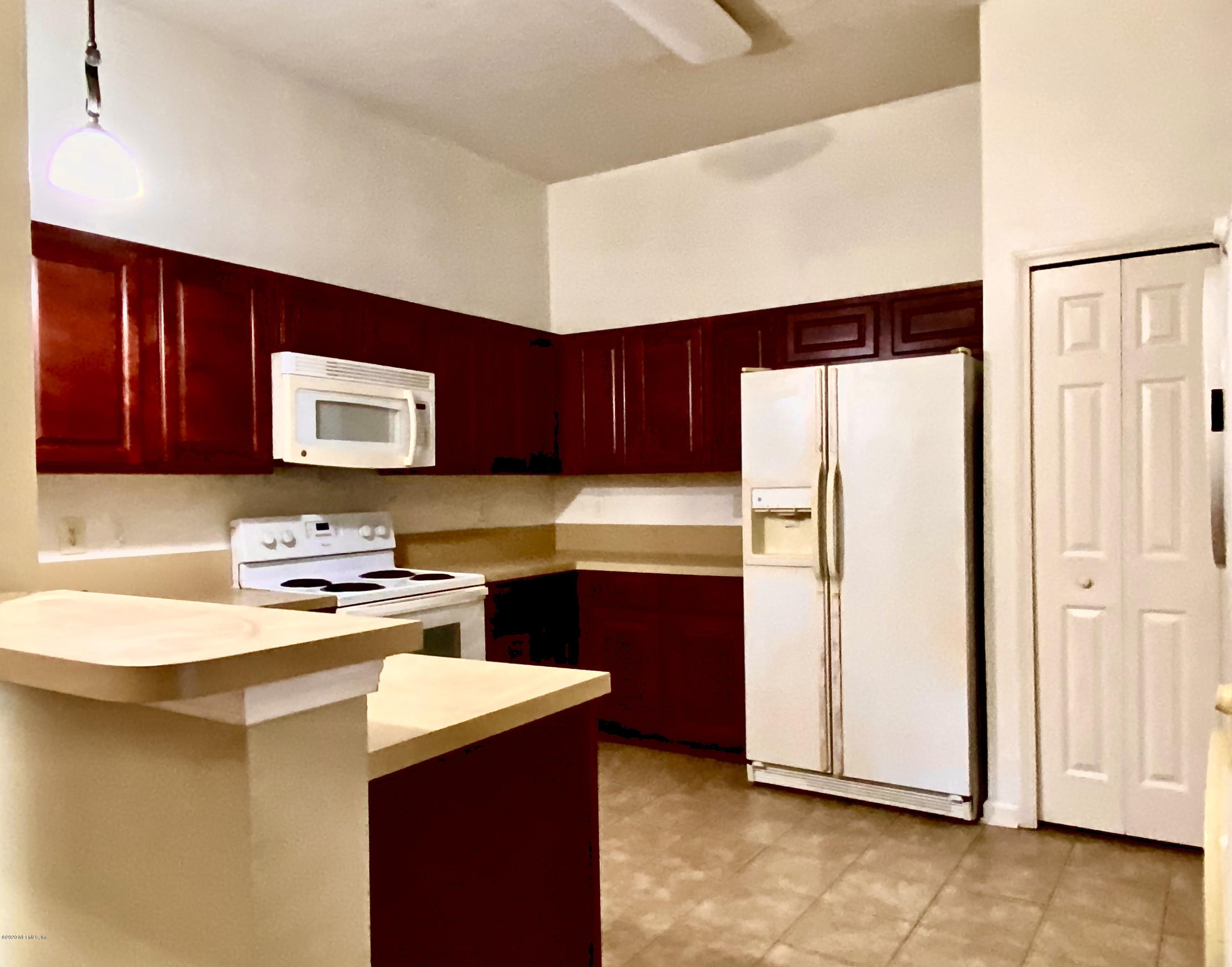 7920 Merrill Road, Unit 707 Jacksonville, FL 32277 - Photo 3 of 13 a kitchen with a sink a stove a refrigerator a microwave oven and cabinets