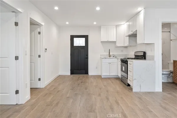 a kitchen with white cabinets and wooden floor