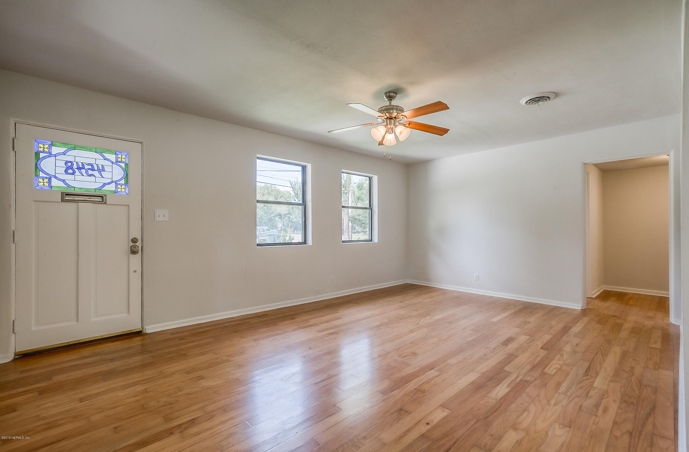 4548 Milstead Road Jacksonville, FL 32210 - Photo 17 of 37 a view of an empty room with a window and wooden floor