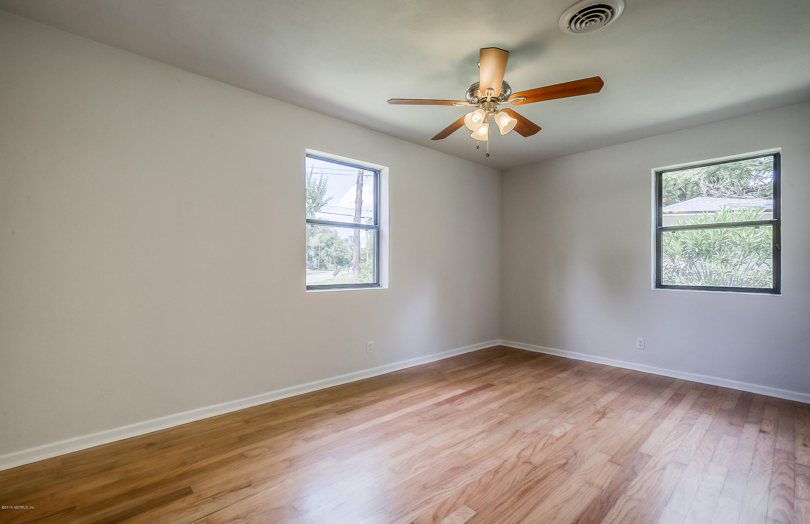 4548 Milstead Road Jacksonville, FL 32210 - Photo 22 of 37 a view of an empty room with wooden floor and a window