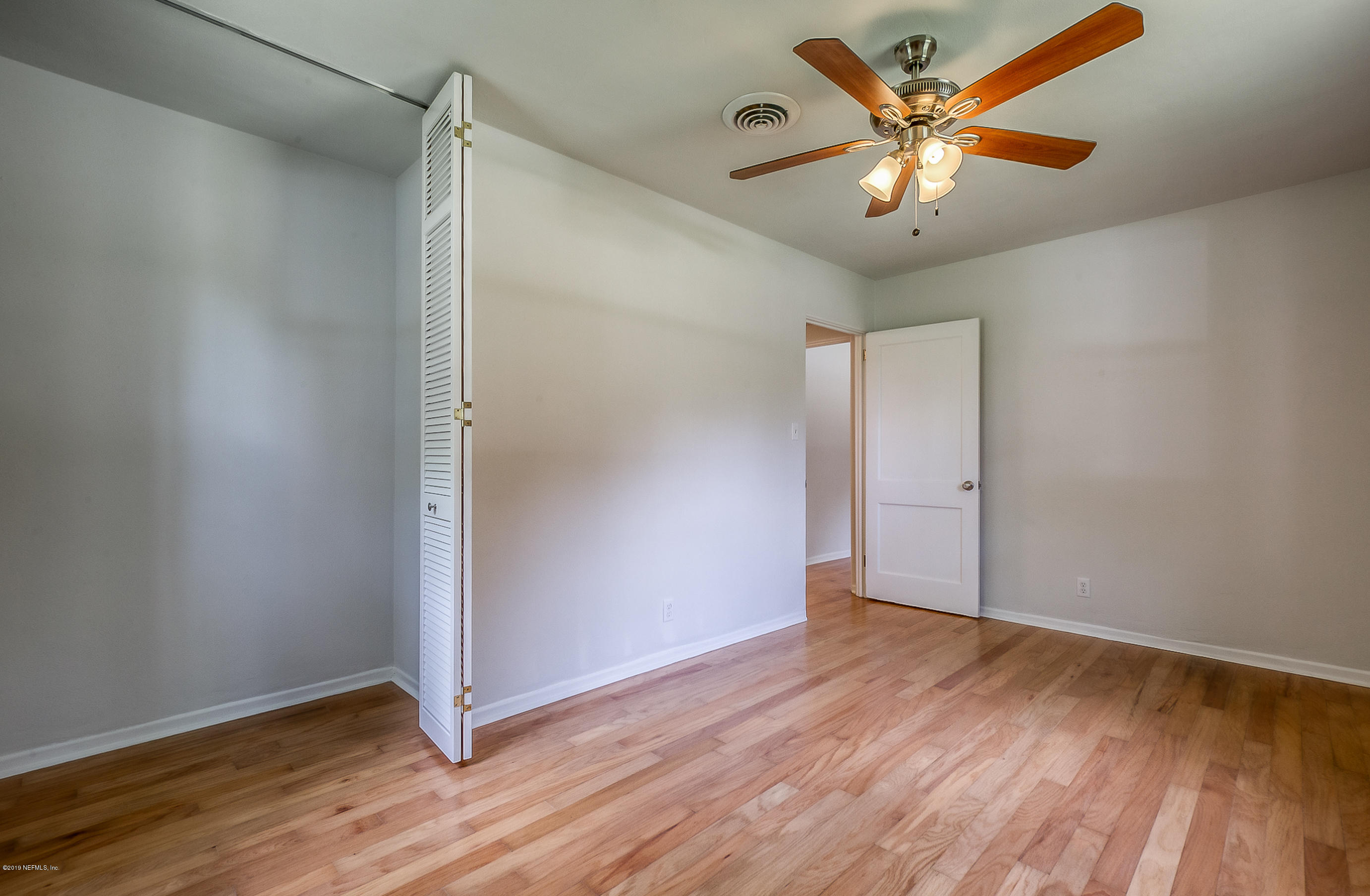 4548 Milstead Road Jacksonville, FL 32210 - Photo 23 of 37 an empty room with wooden floor and a ceiling fan