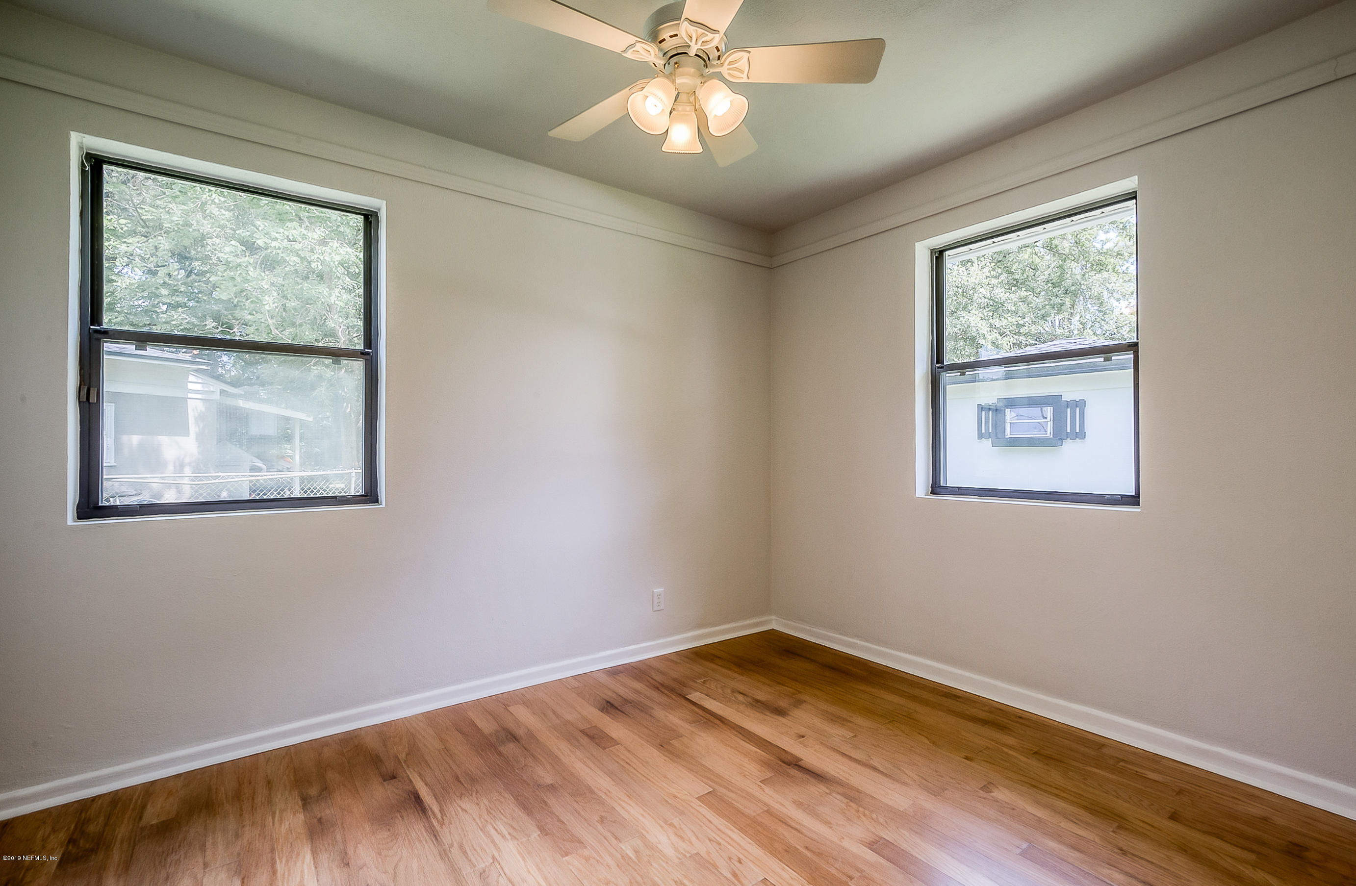 4548 Milstead Road Jacksonville, FL 32210 - Photo 25 of 37 a view of an empty room with a window and wooden floor