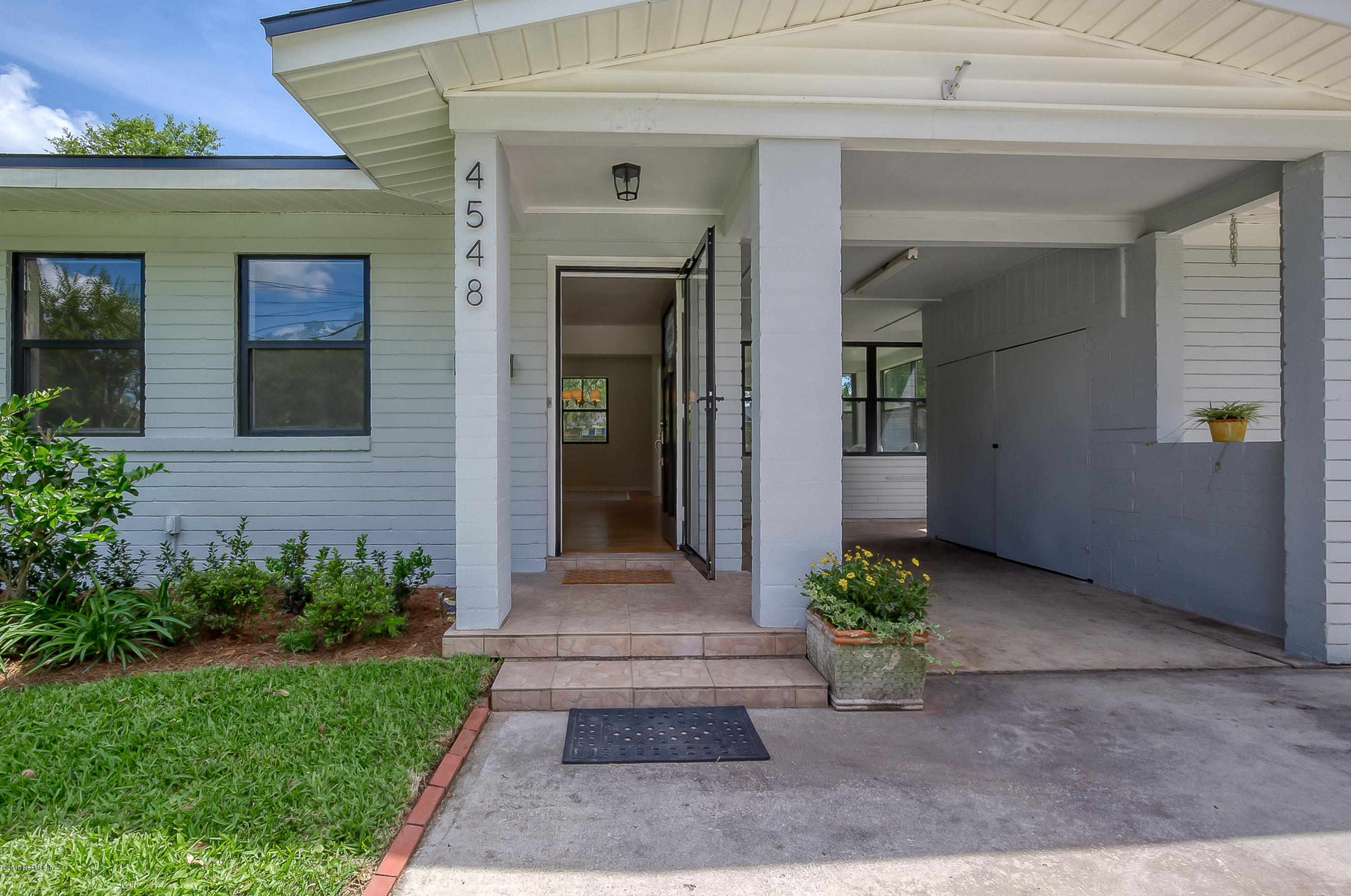 4548 Milstead Road Jacksonville, FL 32210 - Photo 3 of 37 a stone house with potted plants in front of door